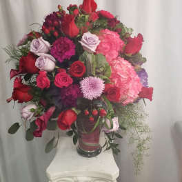 Large bouquet of red, pink, and lavender flowers in a glass vase