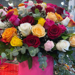 Large bouquet of multicolored roses in a pink box with eucalyptus
