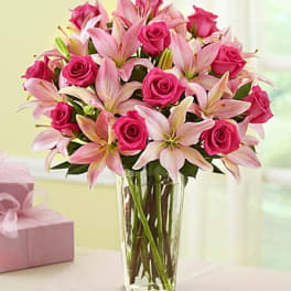 Pink roses and lilies arranged in a clear glass vase