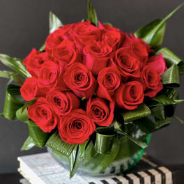 Bouquet of red roses with glossy green leaves in a vase