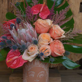 Bouquet of peach roses and pink anthuriums in a terracotta vase