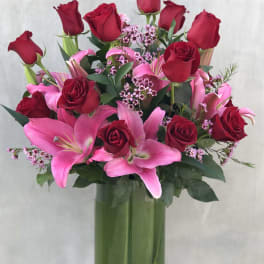 Red roses and pink lilies arranged in a tall glass vase