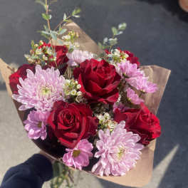 Bouquet of red roses and pale pink chrysanthemums wrapped in brown paper