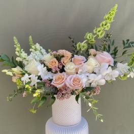 Pastel bouquet of roses and white orchids in a white vase
