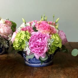 Pink and green floral arrangement in a blue-and-white ceramic container