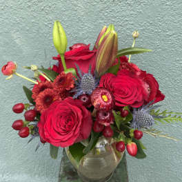 Red roses and lilies arranged in a clear glass vase