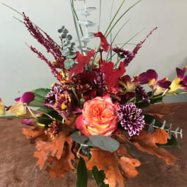 Autumn floral arrangement with a pink rose and purple orchids