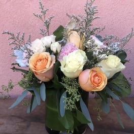 Bouquet of peach, white, and pink roses in a black vase