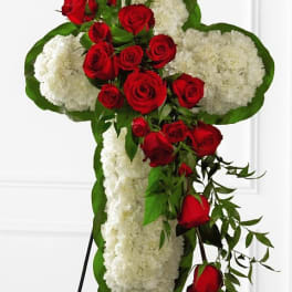 Cross-shaped floral tribute with red roses and white carnations on a stand