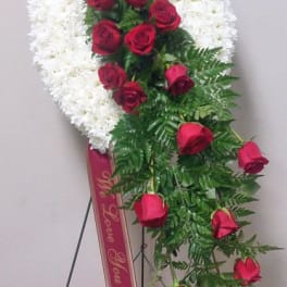 Standing floral wreath with white flowers and red roses on a ribboned easel