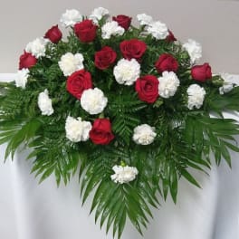 Red roses and white carnations arranged with palm fronds