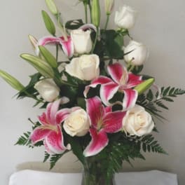 Pink lilies and white roses arranged in a clear glass vase
