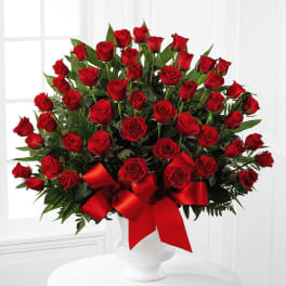 Large bouquet of red roses in a white vase with a red ribbon