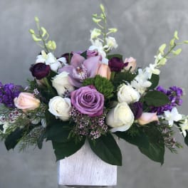 Lavender and white rose arrangement with purple orchids in a white vase