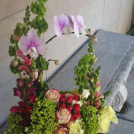 Mixed floral arrangement with pink orchids and roses in a rectangular container