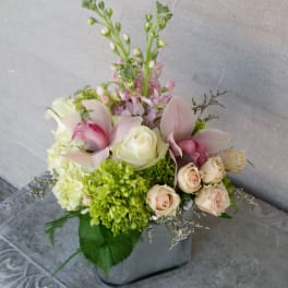 Mixed bouquet with roses, hydrangea, and pink orchids in a square vase