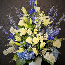Tall blue and yellow floral arrangement in a white vase