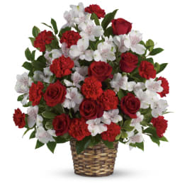 Red roses, red carnations, and white alstroemeria arranged in a woven basket
