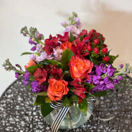 Colorful bouquet of roses and purple flowers in a glass vase