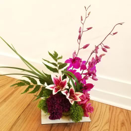 Pink orchid and lily arrangement in a low square container