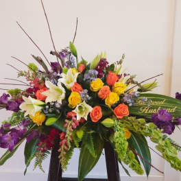 Large mixed bouquet with roses, lilies, and purple flowers in a low container