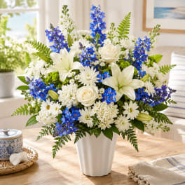 White and blue mixed flower arrangement in a white vase