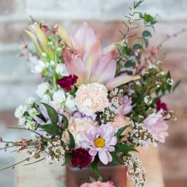 Pastel bouquet in a square vase with lilies, daisies, and carnations