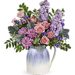 Mixed pink and purple flowers in a blue-and-white ceramic pitcher