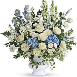 White and blue floral arrangement in a white pedestal vase