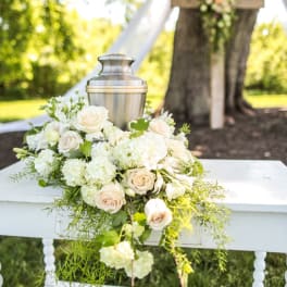 White floral arrangement around a silver urn on a chair