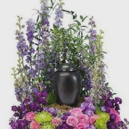 Purple and pink floral arrangement in a black urn vase