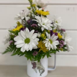 White and yellow daisy bouquet in a white mug