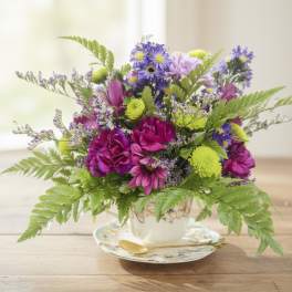 Colorful bouquet of purple and pink flowers in a teacup vase