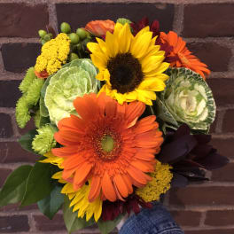 Bouquet of sunflowers, orange gerbera daisies, and green ornamental cabbage