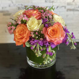 Bouquet of orange, yellow, and purple flowers in a glass vase