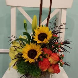 Sunflowers, roses, and lilies arranged in a gray vase