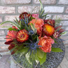 Bouquet of orange and pink flowers with blue thistle-like accents