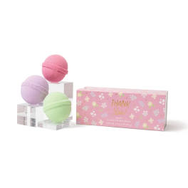 Three pastel bath bombs beside a pink floral gift box