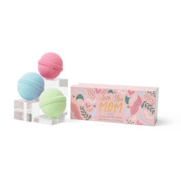 Three pastel bath bombs beside a pink gift box labeled Love You Mom.