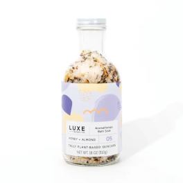 Bottle of honey almond aromatherapy bath soak with dried botanicals