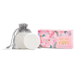 A mesh bag with a round white shower steamer and a pink gift box