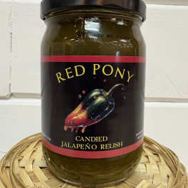 Jar of candied jalapeño relish with a black lid on a woven tray