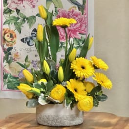 Yellow tulips and gerbera daisies arranged in a glittered vase