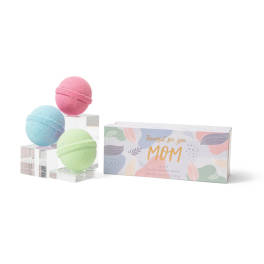 Three pastel bath bombs beside a gift box labeled for Mom