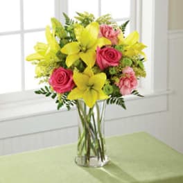 Yellow lilies and pink roses in a clear glass vase