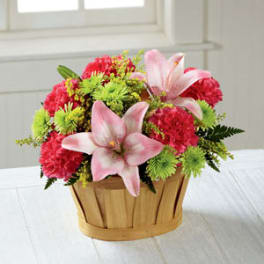 Pink lilies and red-green mixed flowers in a wooden basket