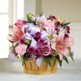 Mixed pink and purple flowers in a basket with a lavender ribbon