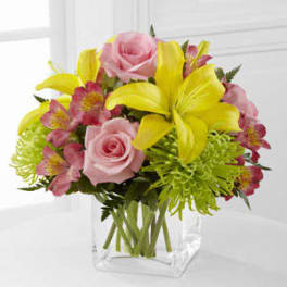 Bouquet of pink roses and yellow lilies in a clear glass vase