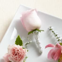 Pink rose boutonniere and matching floral accessories on a white tray