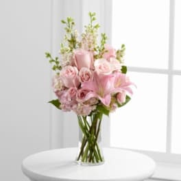 Pink roses and lilies arranged in a clear glass vase